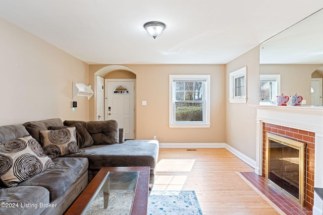 living room featuring a brick fireplace, plenty of natural light, and light wood-type flooring