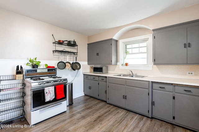 kitchen featuring wood-type flooring, white gas range, gray cabinetry, and sink