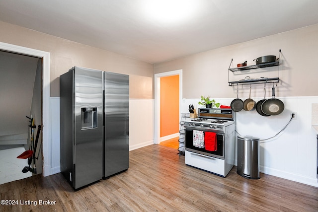 kitchen featuring stainless steel fridge with ice dispenser, white gas stove, and light hardwood / wood-style floors