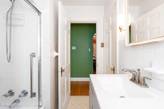 bathroom featuring vanity, a shower with shower door, and tile walls