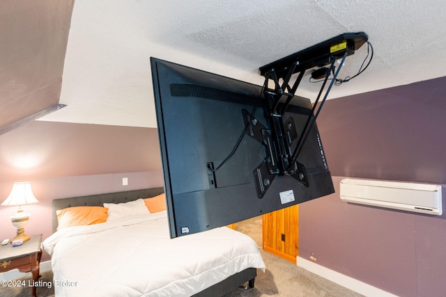 bedroom featuring light carpet, a wall mounted air conditioner, and a textured ceiling