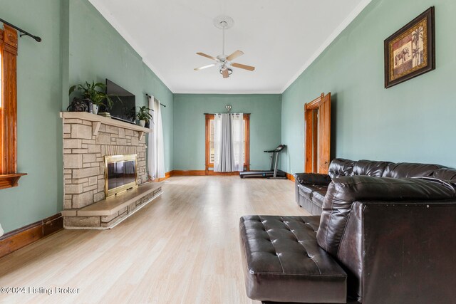 living room with ceiling fan, light hardwood / wood-style floors, crown molding, and a fireplace