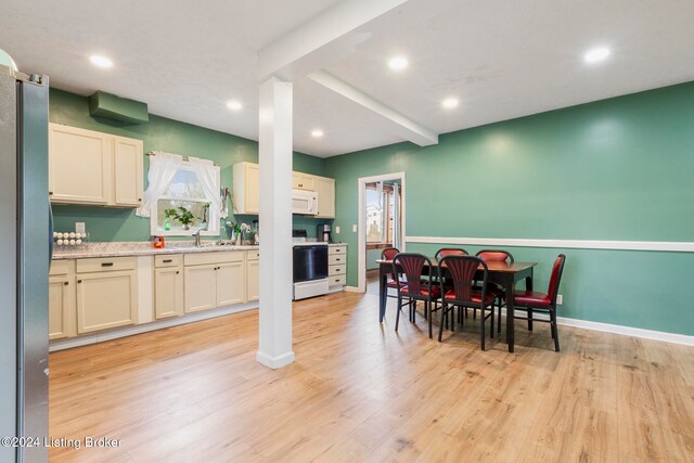 kitchen with white appliances, sink, light stone countertops, beamed ceiling, and light hardwood / wood-style floors