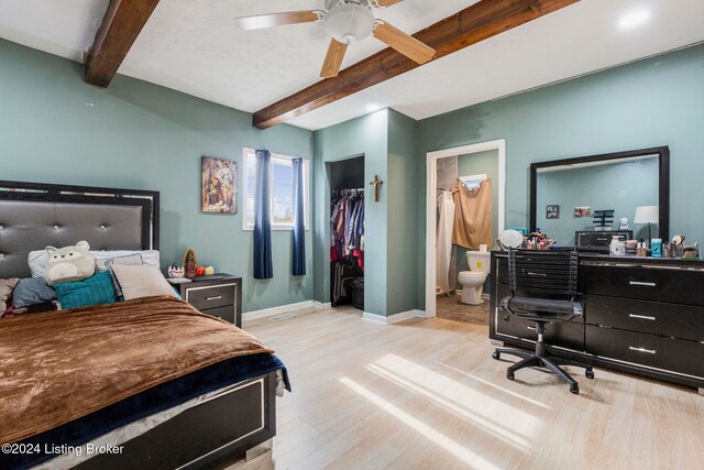 bedroom with ensuite bathroom, light hardwood / wood-style flooring, ceiling fan, beam ceiling, and a closet