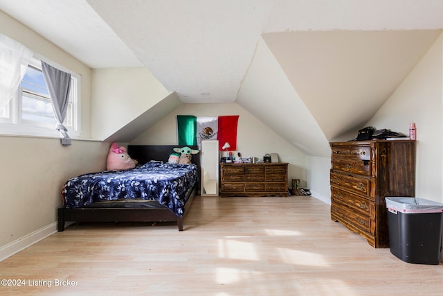 bedroom with vaulted ceiling and light hardwood / wood-style flooring