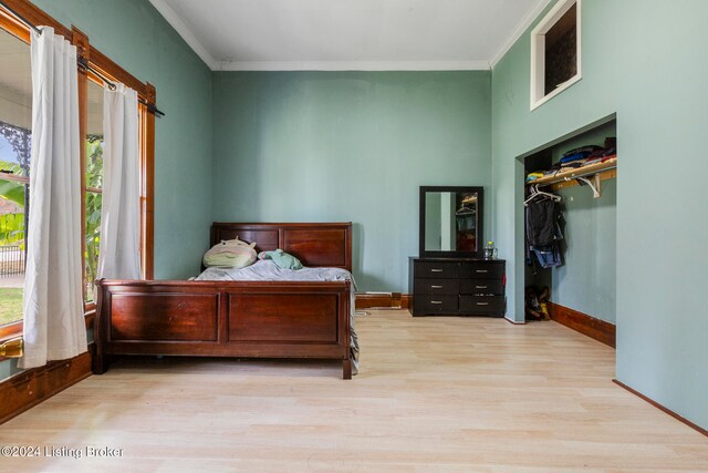 bedroom with light hardwood / wood-style flooring, multiple windows, and crown molding