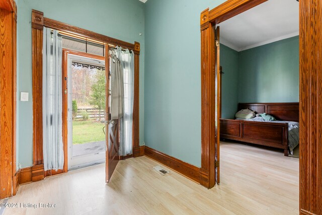 foyer with crown molding and light hardwood / wood-style flooring