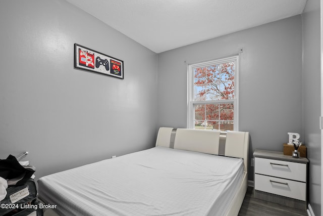 bedroom featuring a textured ceiling and dark hardwood / wood-style floors