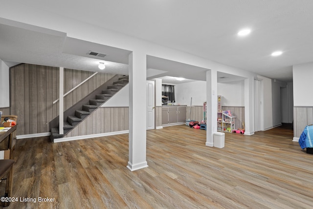 basement with wood walls and wood-type flooring