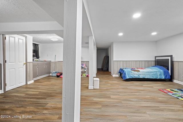 bedroom with wood walls, light hardwood / wood-style floors, and a textured ceiling