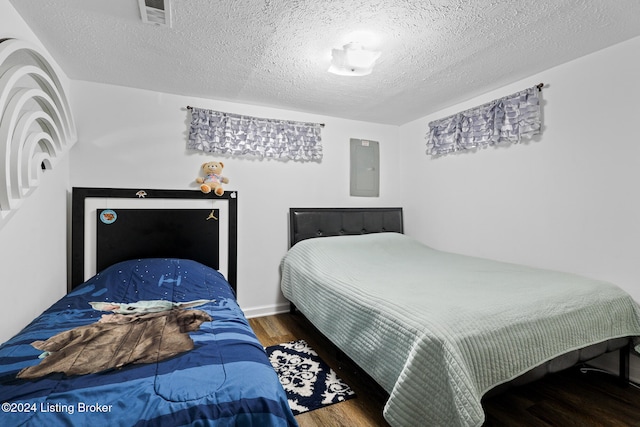 bedroom with electric panel, wood-type flooring, and a textured ceiling