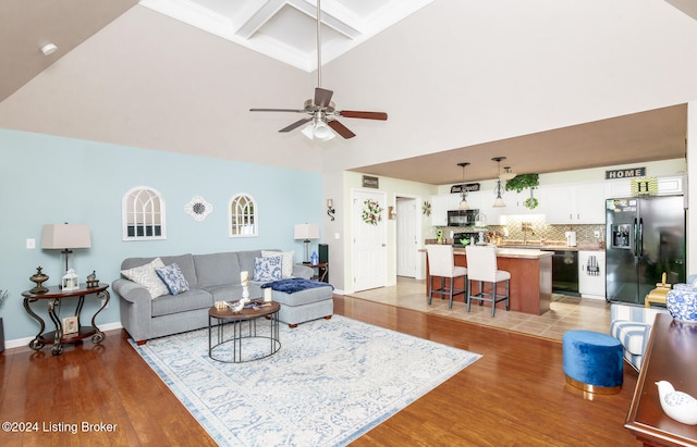 living room with coffered ceiling, ceiling fan, high vaulted ceiling, light hardwood / wood-style flooring, and beamed ceiling