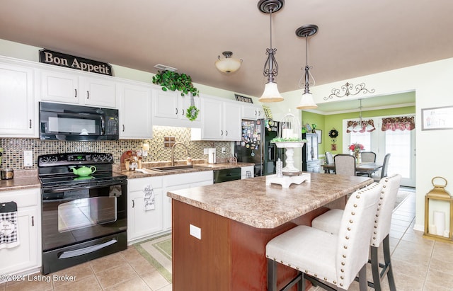 kitchen featuring pendant lighting, a center island, black appliances, sink, and white cabinetry