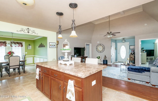 kitchen featuring light stone counters, ceiling fan, pendant lighting, light hardwood / wood-style flooring, and a kitchen island