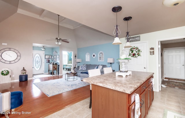 kitchen with ceiling fan, hanging light fixtures, light tile patterned floors, beamed ceiling, and a kitchen island