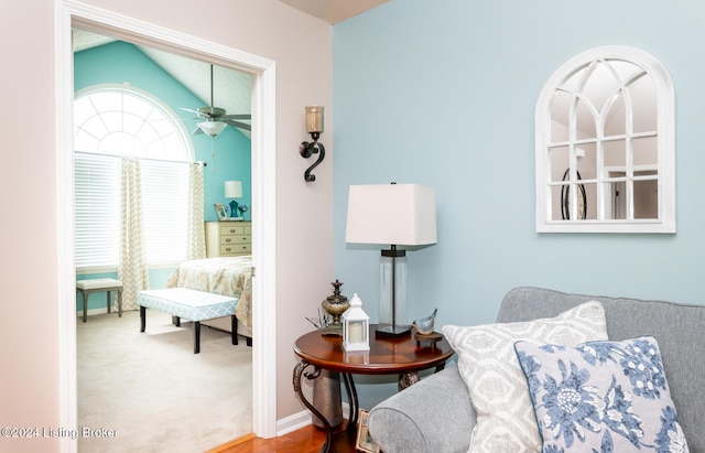 living area featuring carpet flooring, vaulted ceiling, and ceiling fan