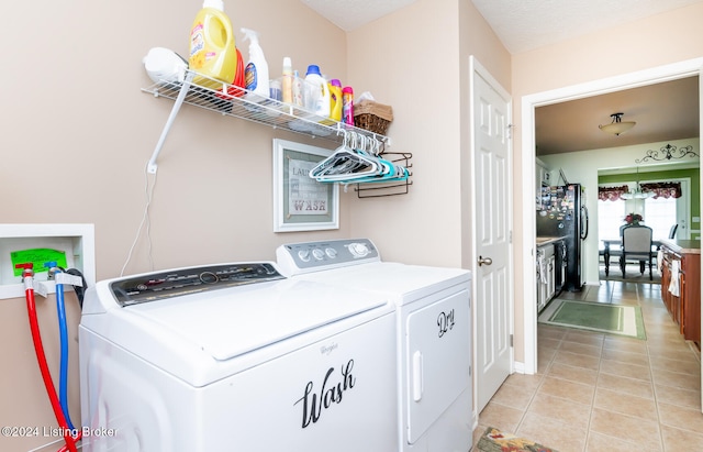 washroom featuring washer and clothes dryer, light tile patterned floors, and a textured ceiling