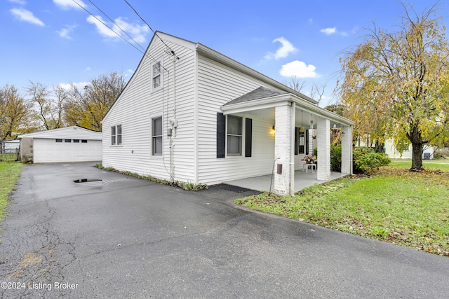 view of side of home featuring a yard, an outbuilding, a porch, and a garage