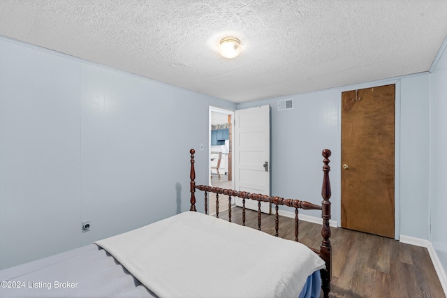 bedroom with dark hardwood / wood-style flooring and a textured ceiling