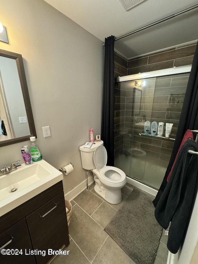 bathroom featuring tile patterned flooring, vanity, toilet, and a shower with shower door