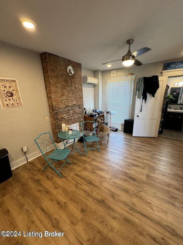 unfurnished dining area with wood-type flooring, an AC wall unit, and ceiling fan