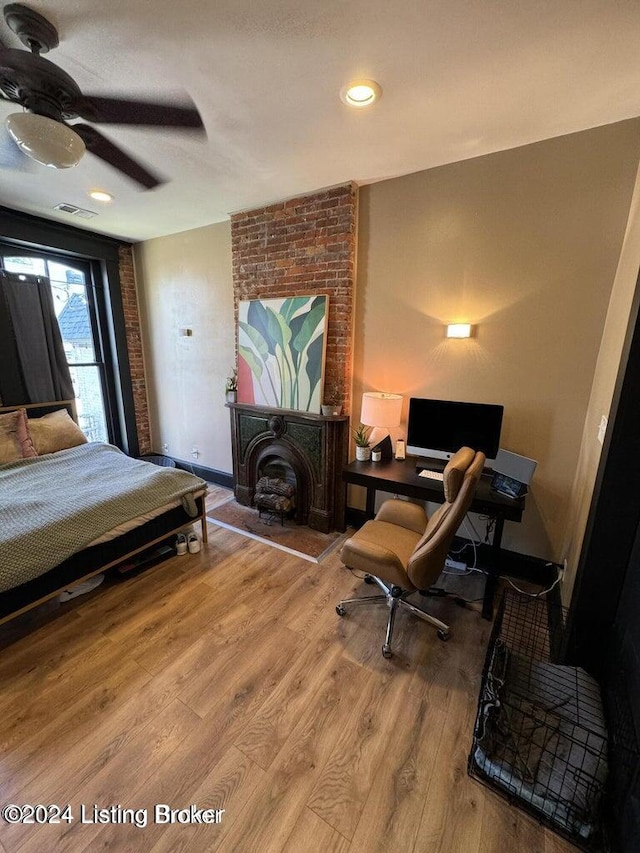 bedroom with hardwood / wood-style flooring, ceiling fan, and a fireplace