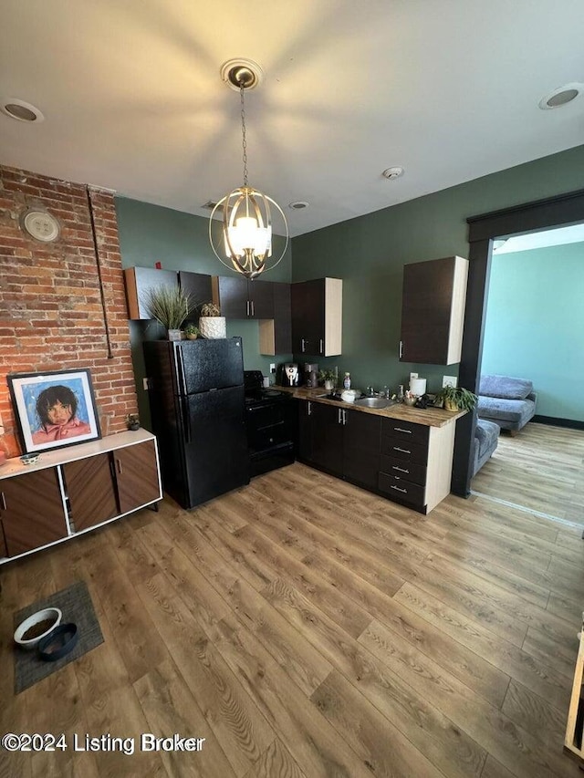 kitchen featuring a notable chandelier, black appliances, sink, decorative light fixtures, and light hardwood / wood-style floors