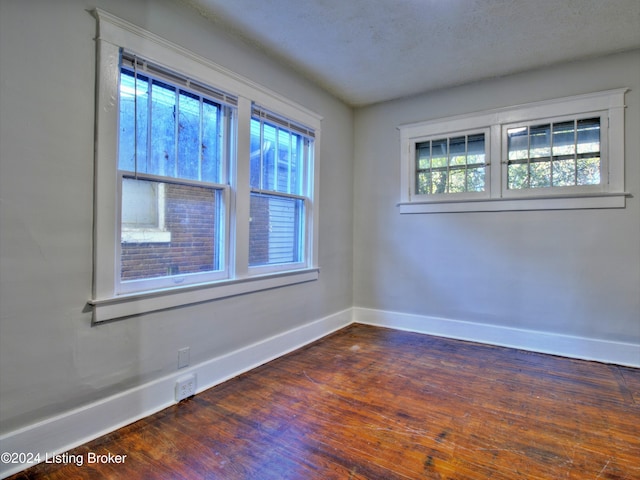 spare room with a healthy amount of sunlight, dark hardwood / wood-style flooring, and a textured ceiling