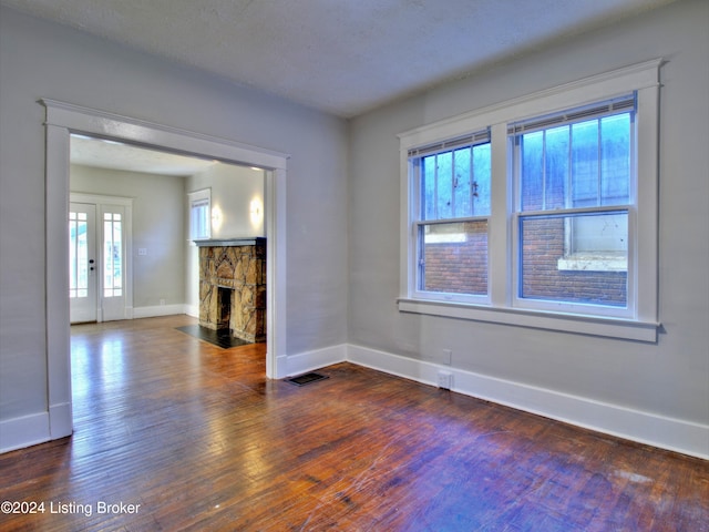 unfurnished living room featuring a textured ceiling, dark hardwood / wood-style floors, and a fireplace