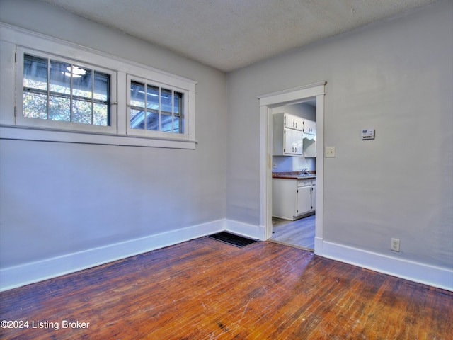 empty room with wood-type flooring and a textured ceiling