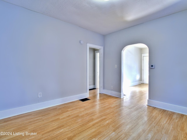 empty room featuring a textured ceiling and light hardwood / wood-style floors