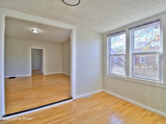 unfurnished room featuring hardwood / wood-style floors and a textured ceiling