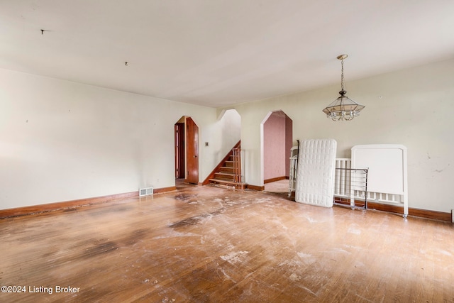 empty room with an inviting chandelier and hardwood / wood-style flooring