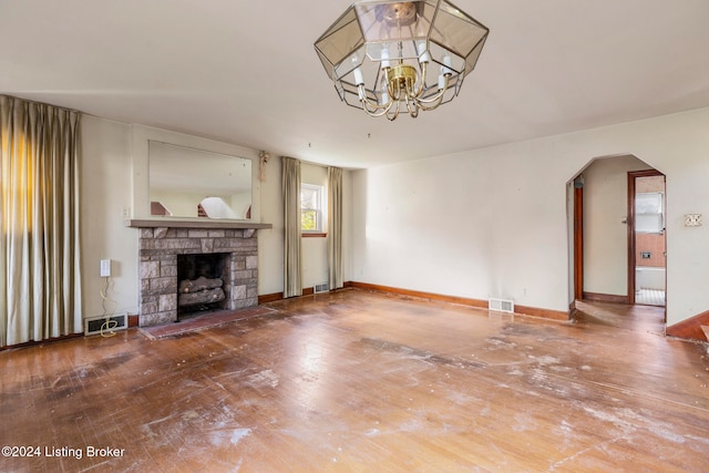 unfurnished living room featuring a notable chandelier and a stone fireplace