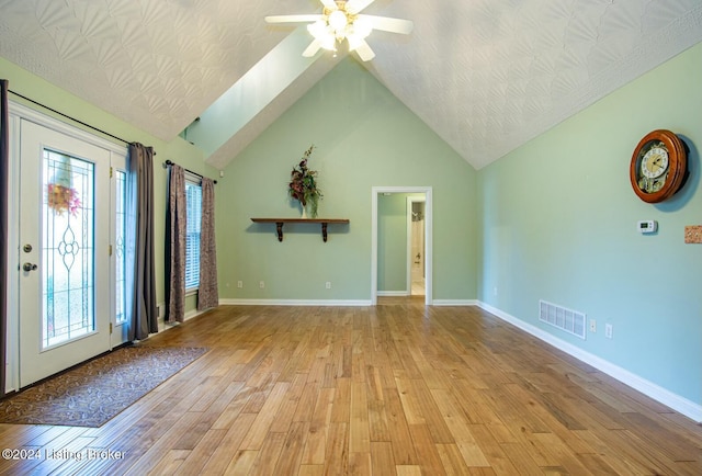 interior space with lofted ceiling with skylight, light hardwood / wood-style flooring, ceiling fan, and a healthy amount of sunlight