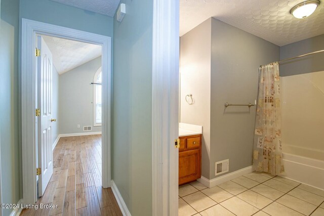 bathroom with shower / bath combo with shower curtain, hardwood / wood-style floors, vanity, and a textured ceiling