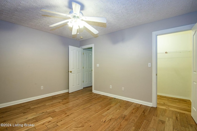 empty room featuring ceiling fan, light hardwood / wood-style floors, and a textured ceiling