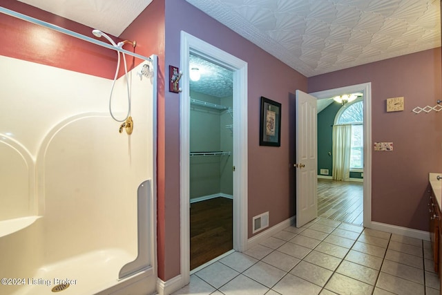 bathroom with tile patterned flooring, vanity, and walk in shower