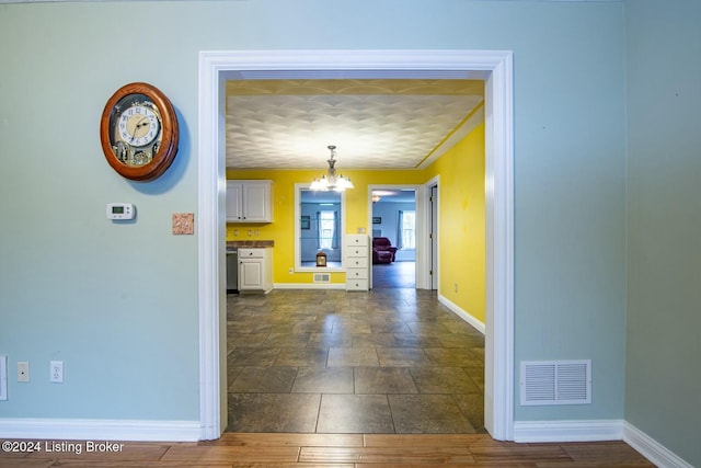 hall with ornamental molding, dark wood-type flooring, and a notable chandelier