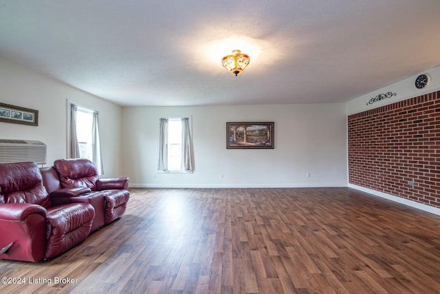 living room featuring a textured ceiling, dark wood-type flooring, and brick wall