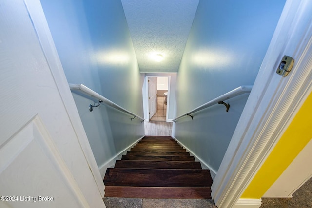 staircase featuring hardwood / wood-style flooring and a textured ceiling