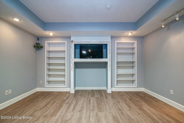 unfurnished living room featuring a textured ceiling, light wood-type flooring, and track lighting