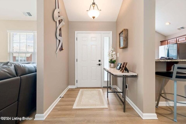 foyer with light hardwood / wood-style floors and vaulted ceiling