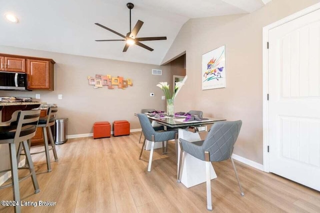 dining room featuring ceiling fan, light hardwood / wood-style floors, and vaulted ceiling