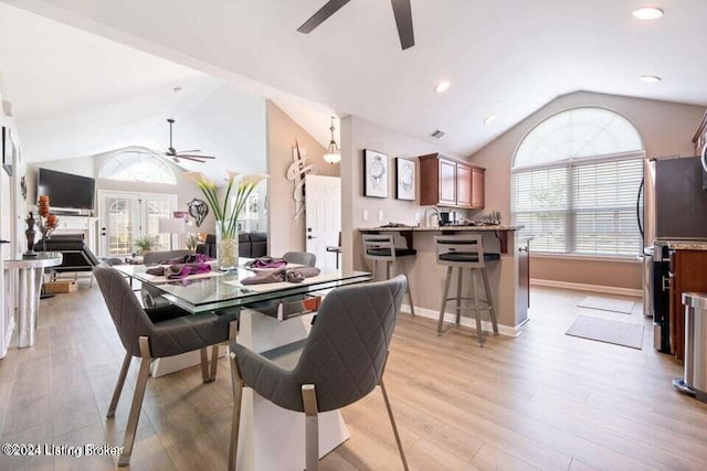 dining space featuring light hardwood / wood-style floors, high vaulted ceiling, and ceiling fan