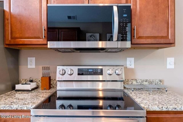 kitchen with light stone counters and appliances with stainless steel finishes