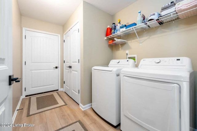 laundry area with separate washer and dryer and light hardwood / wood-style flooring