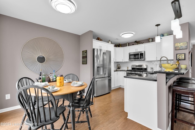 kitchen featuring backsplash, white cabinets, light wood-type flooring, appliances with stainless steel finishes, and kitchen peninsula