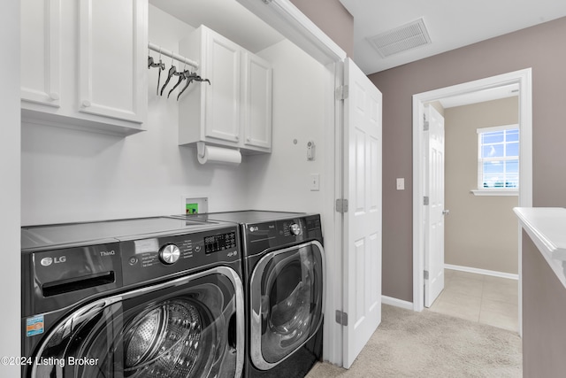 laundry area featuring cabinets, washing machine and dryer, and light colored carpet