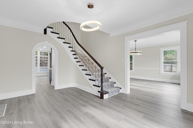 stairs featuring a chandelier, hardwood / wood-style floors, and ornamental molding